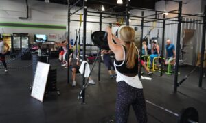 woman lifting barbell in workout class